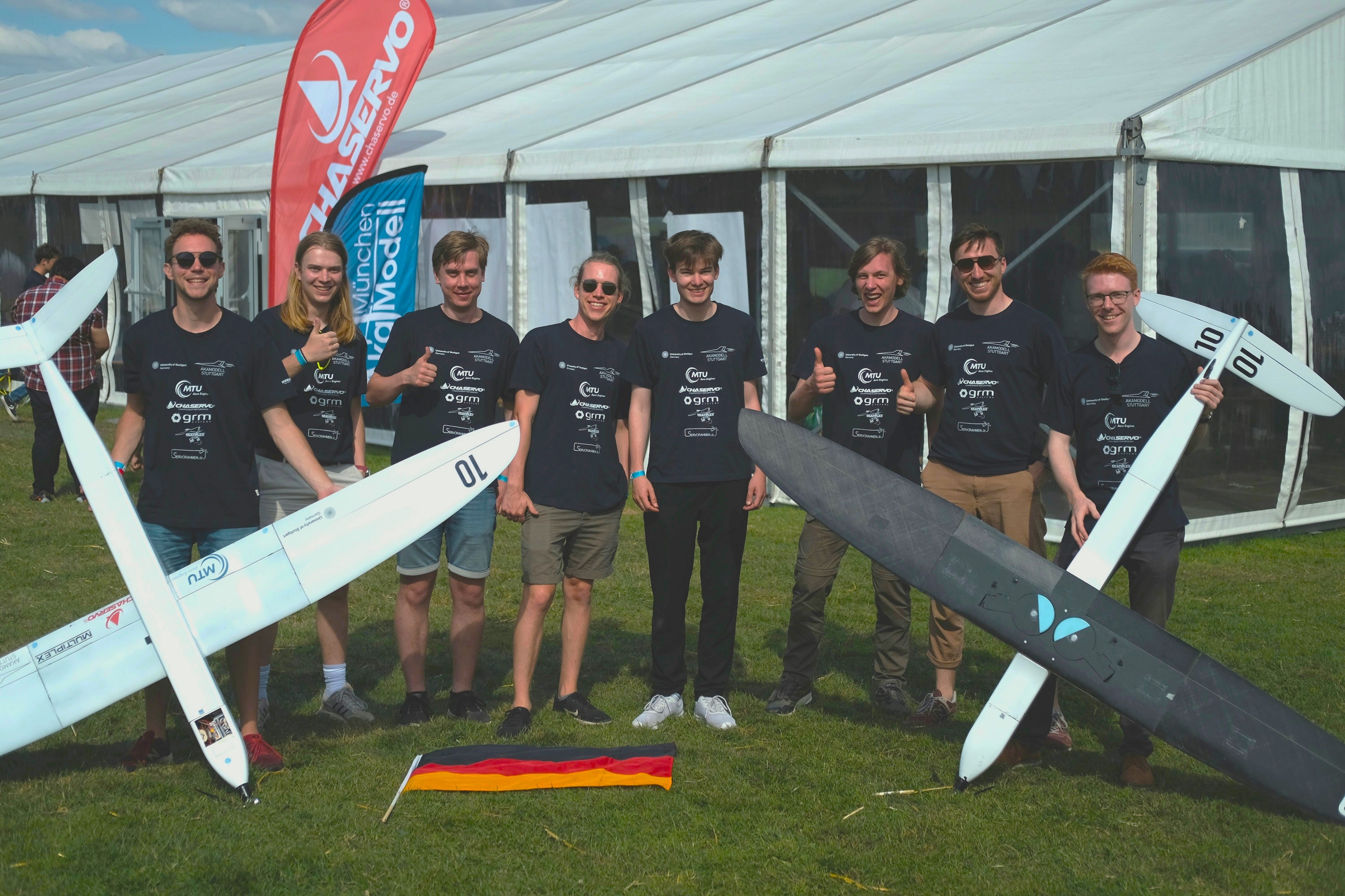 Das Team posiert für ein Gruppenfoto, mit beiden Modellflugzeugen.