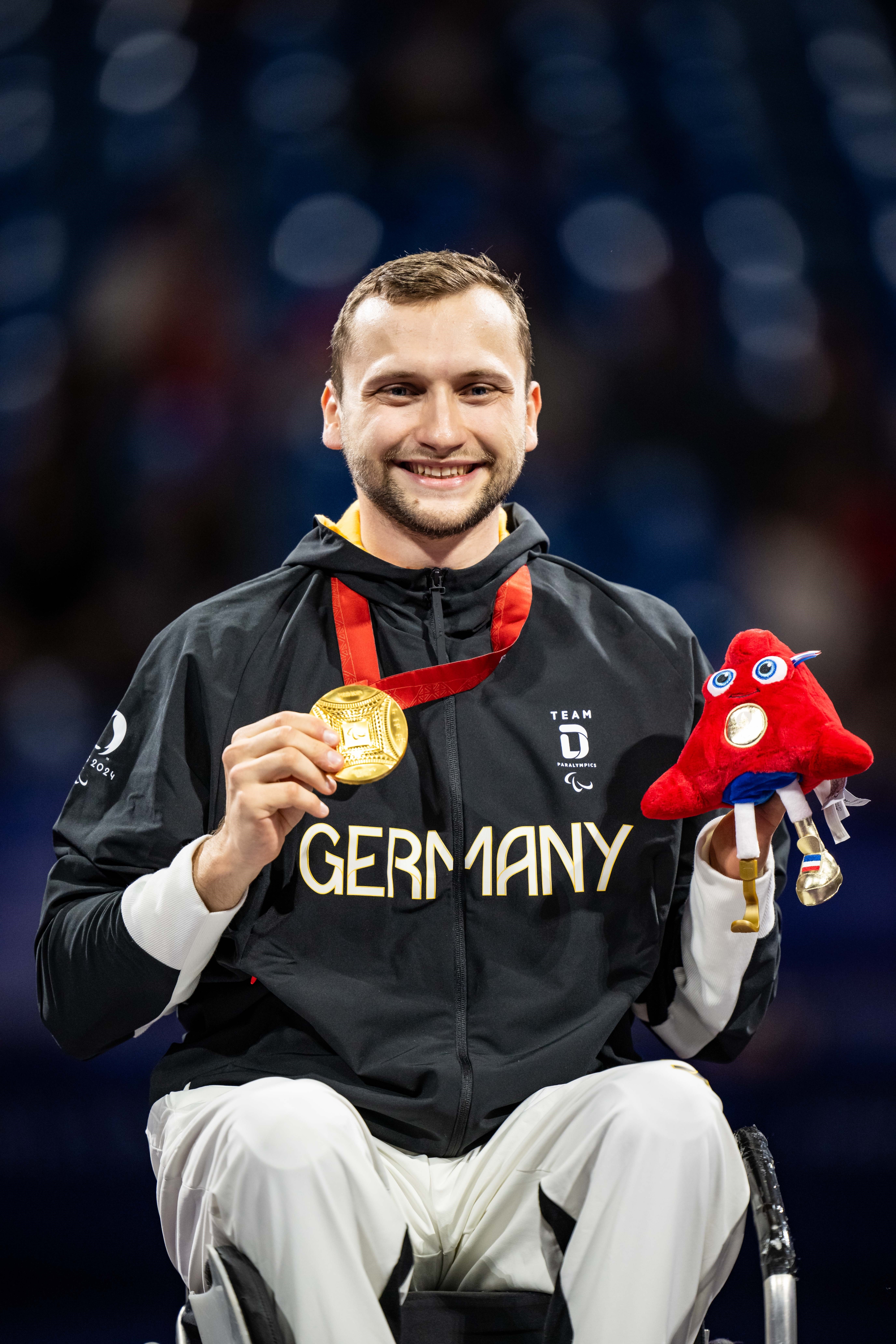 Maurice Schmidt nach der Siegerehrung mit seiner Goldmedaille und dem Paralympics-Maskottchen.